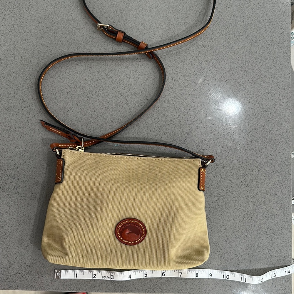 Dooney & Bourke canvas crossbody in tan. NWOT. Never used with paperwork.